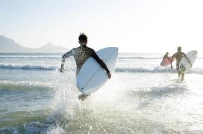 Young surfers running into the ocean with surf boards in their hands
