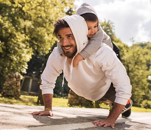 A young father exercising push-ups with his son on his back