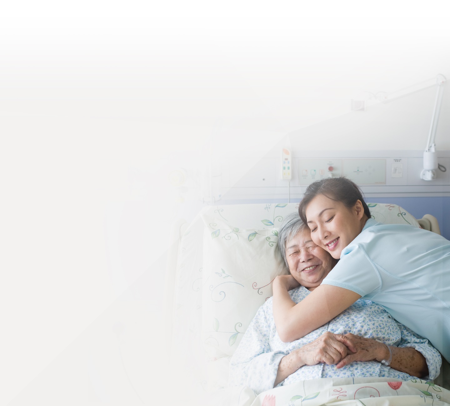 Νοσοκόμα αγκαλιάζει ηλικιωμένη γυναίκα στο κρεβάτι νοσοκομείου