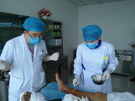 Huo Jizhen behandelt die Wunde eines Patienten zusammen mit einem Arzt.