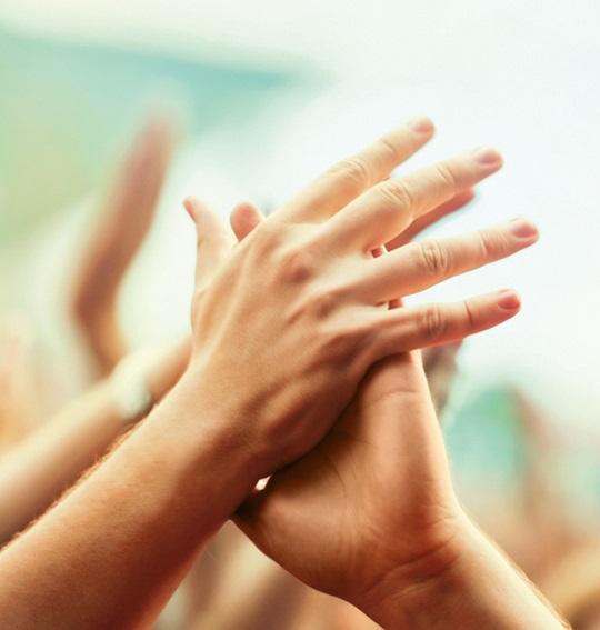 Two hands touching. Other hands in the background.