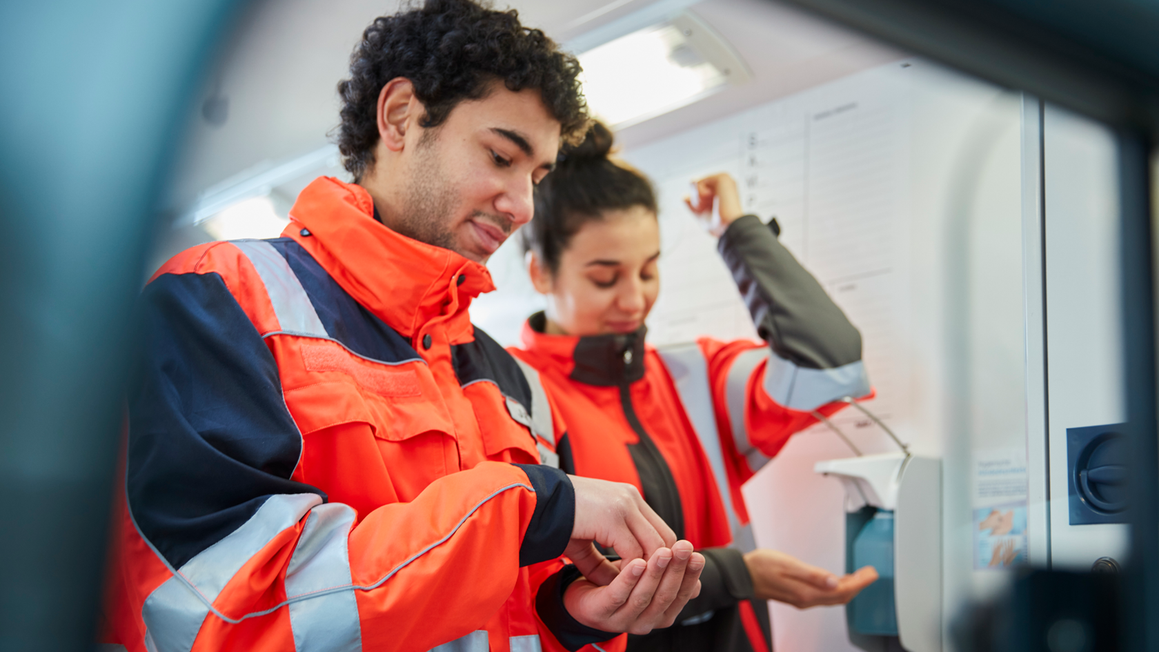 Zwei Rettungssanitaeter beim desinfizieren der Haende