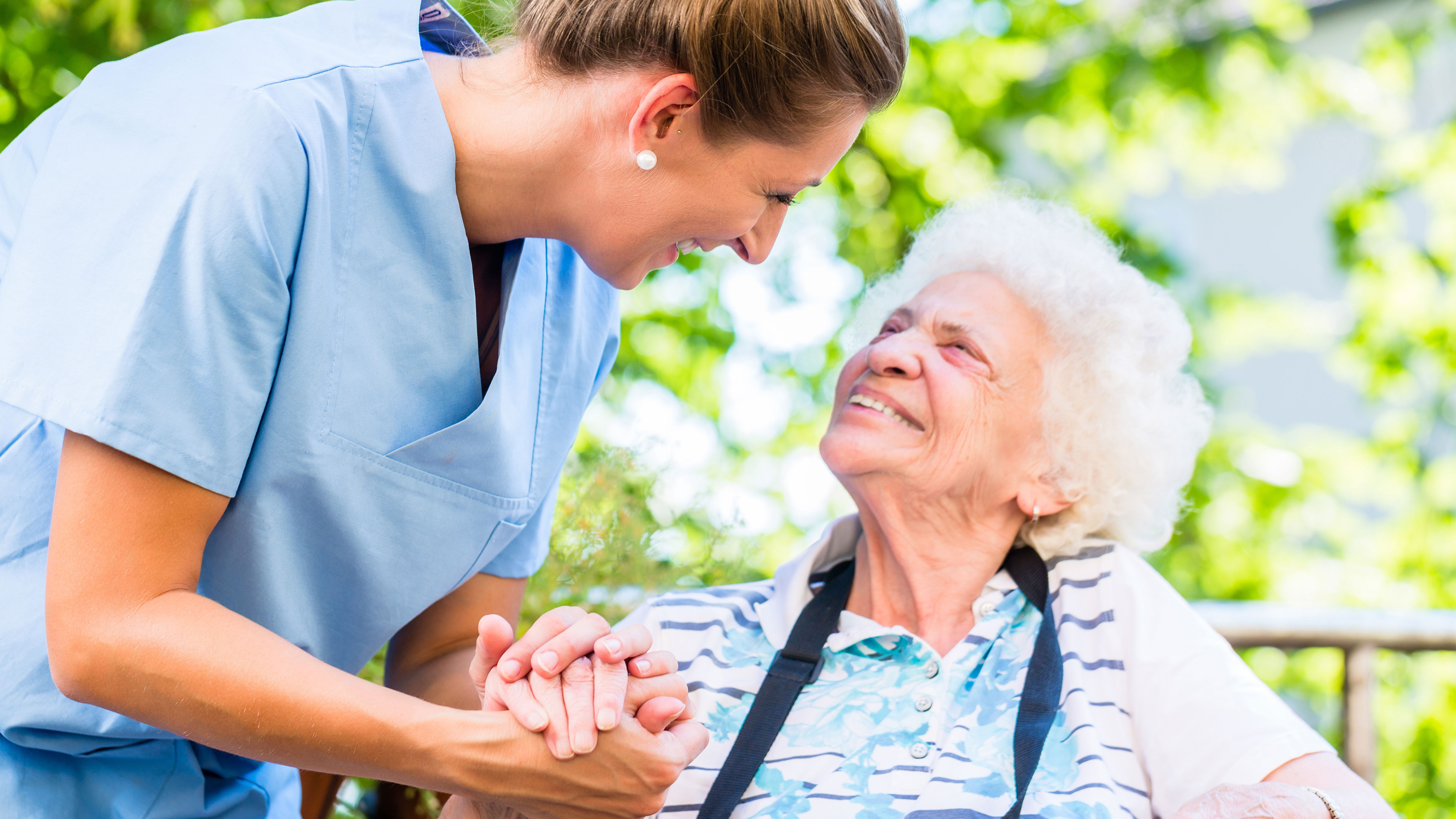 Pflegerin mit Seniorin im Garten