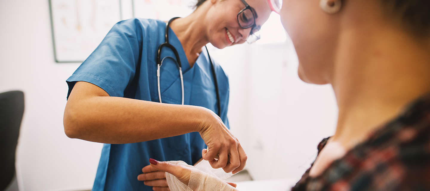 Una enfermera aplicando un vendaje en el brazo de una mujer en un consultorio médico