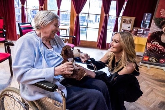 Tatiana Gregor Brzobohata kneeling next to a woman sitting in a wheelchair talking to her