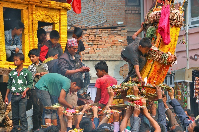 Nepalese people handing offerings up to a wagon. 