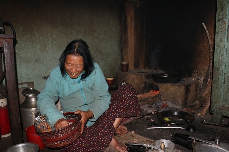 Nepalese woman cooking sitting in her kitchen. 