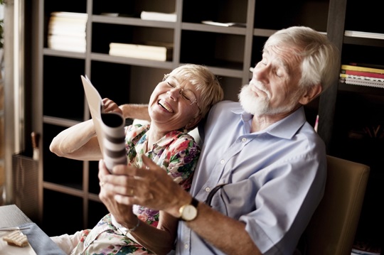 Happy Senior Couple Reading Magazine in Bar