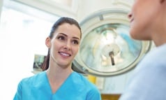 A female nurse talking to a patient holding her hand.