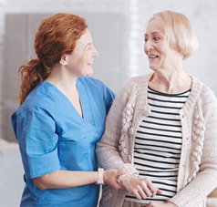 Pflegerin stützt Seniorin beim Laufen