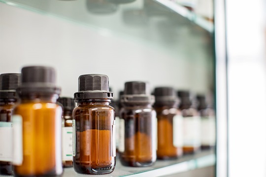 Medicine bottles made of brown glass with white labels in a shelf.
