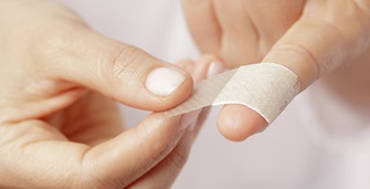 Hand wrapping plaster around finger.