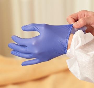 Two hands putting on sterile gloves.