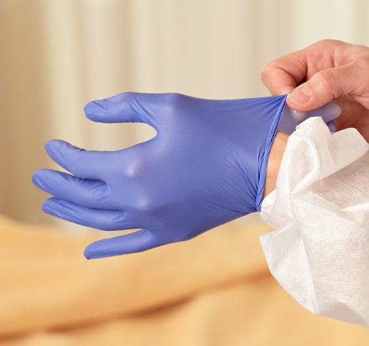Two hands putting on sterile gloves.