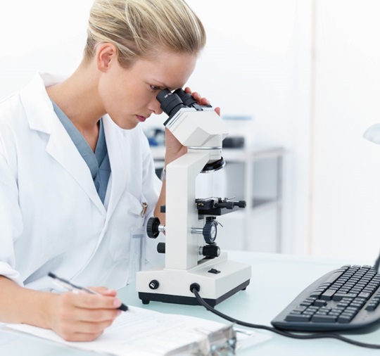 Woman is looking through a microscope
