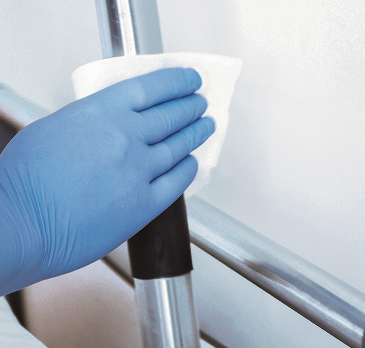 Hand mit blauen Handschuhen desinfiziert Bettgestell