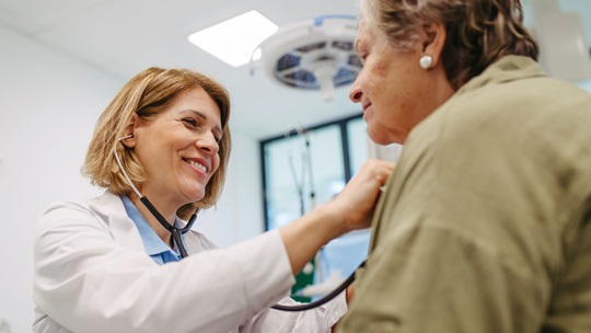 Arztin horcht Patientin mit einem Stethoskop ab