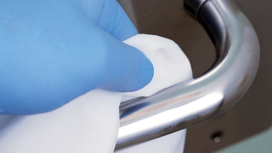 behandschuhte Hand desinfiziert Griff mit einem Tuch