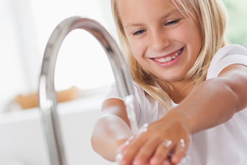 Mädchen wäscht sich die Hände unter dem Wasserhahn