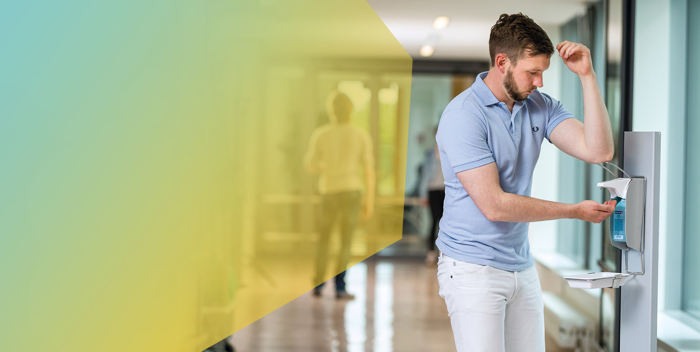 Hospital staff disinfects hands at a dispenser