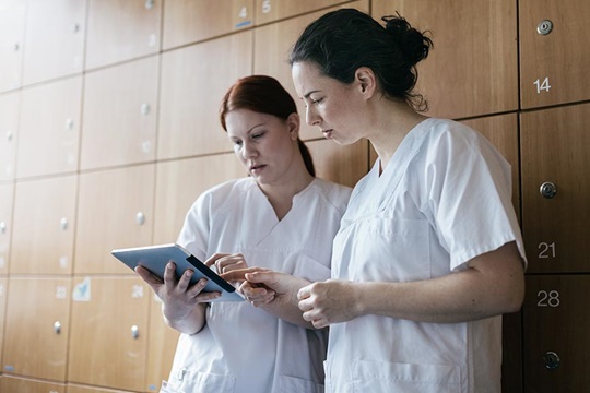 Two nurses discussing information on iPad