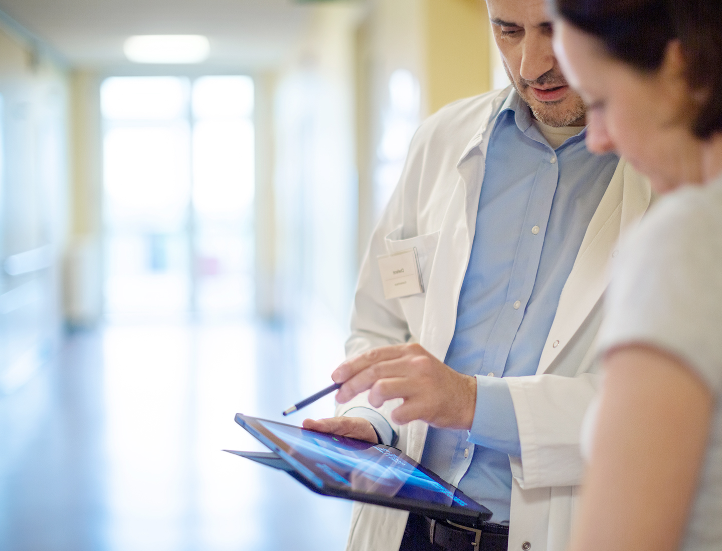 Doctor talking to visitor while showing something on tablet