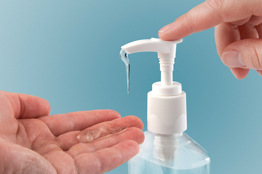 A man takes disinfectant from a dispenser.