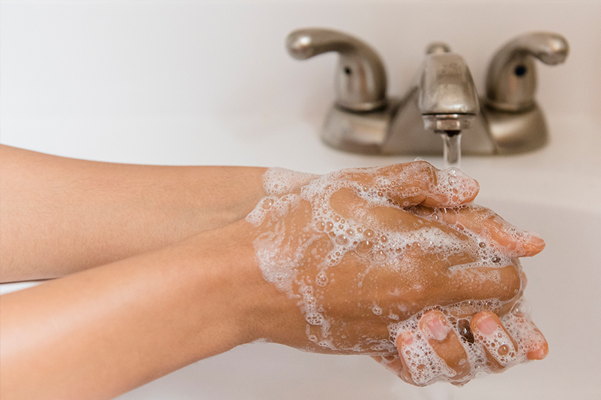 A woman is washing her hands at a sink.