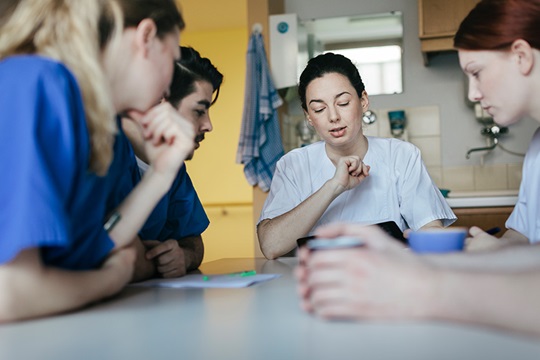 Several nursing staff sitting at the table and talking.