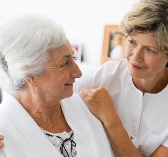 A women, dressed in a nurse’s coat is taking care for an elderly woman