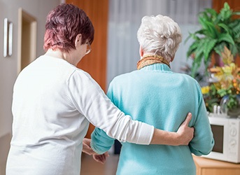 Pflegerin stützt Seniorin beim Gehen