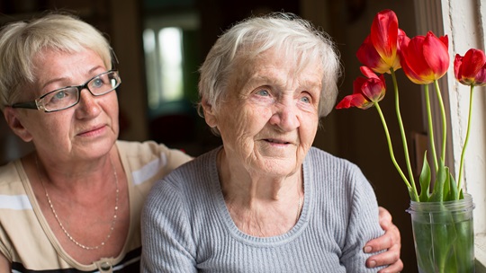 Frau legt den Arm um die Schulter einer Seniorin