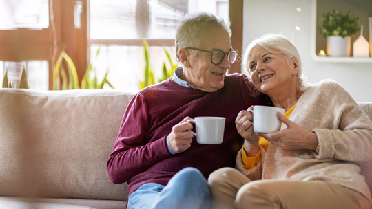 Senioren mit Kaffetassen auf dem Sofa