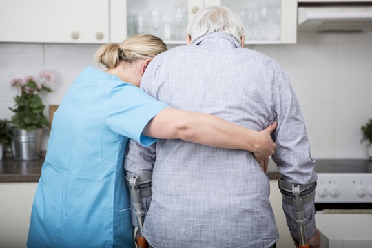 Pflegerin hilft Senior beim Gehen