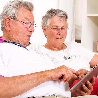 Aelteres Ehepaar auf dem Sofa mit einem Tablet in der Hand