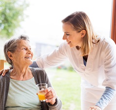 Pflegekraft spricht mit Seniorin