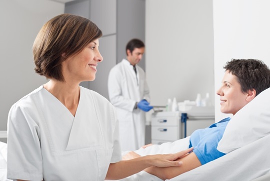 nurse helping a patient in a hospital while putting her hand on the patients arm