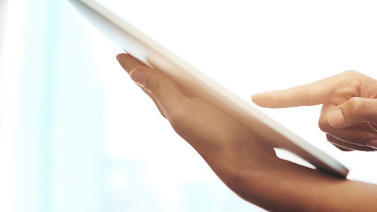 Hand einer Pflegerin tippt auf ein Notepad