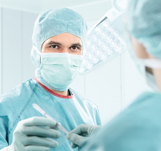 A doctor, dressed in workwear, is passing a scalpel to another doctor, during an operation.