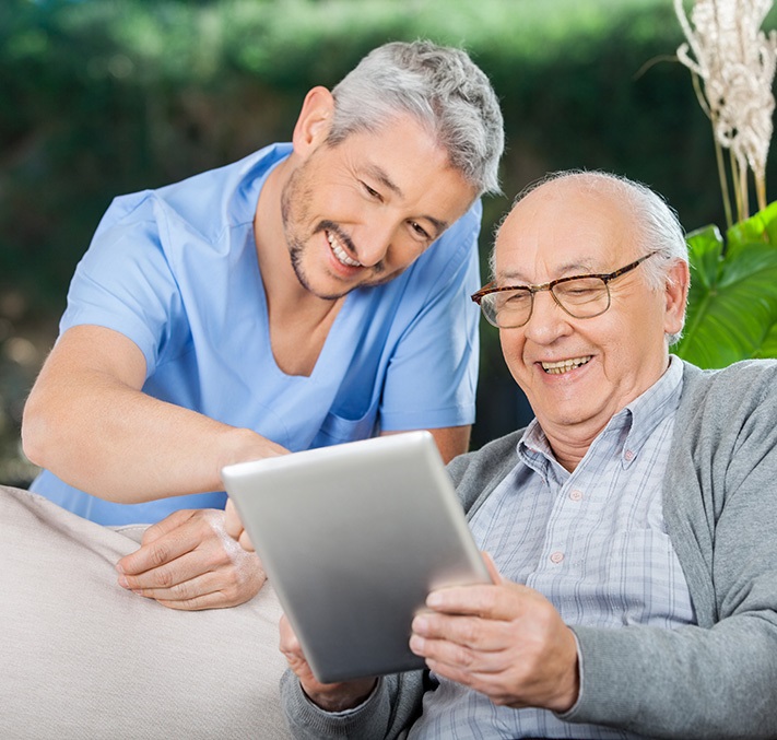 Mann zeigt Senior etwas auf dem Tablet