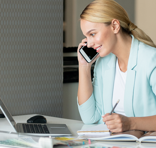 Business Frau am Handy vor Laptop