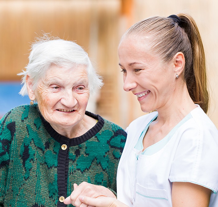 Pflegerin hält Hand einer Seniorin