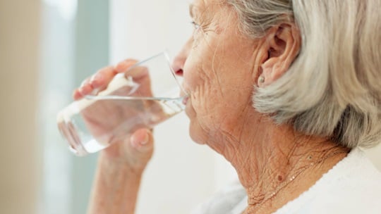 Seniorin trinkt wasser