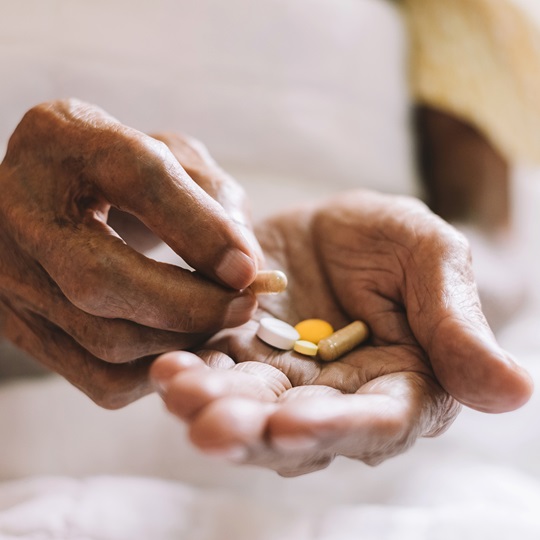 in einer Seniorenhand liegen mehrere Tabletten