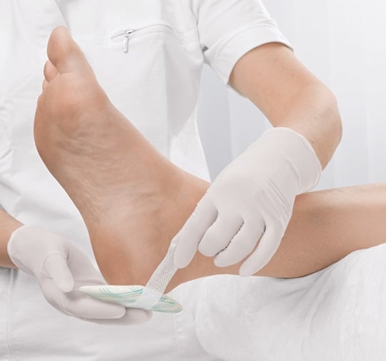 A nurse treating a wound on the foot