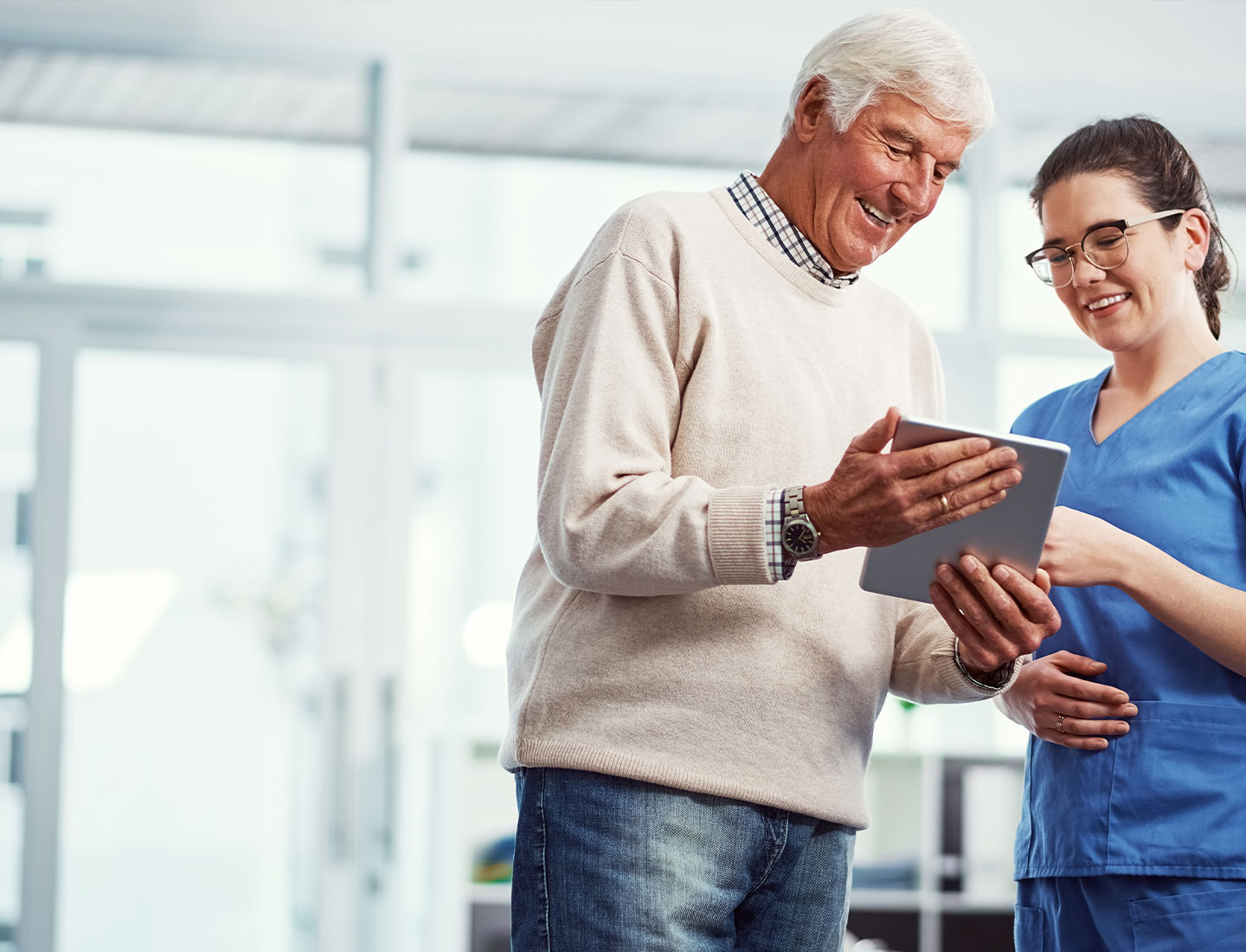 Senior and caregiver look into the tablet together