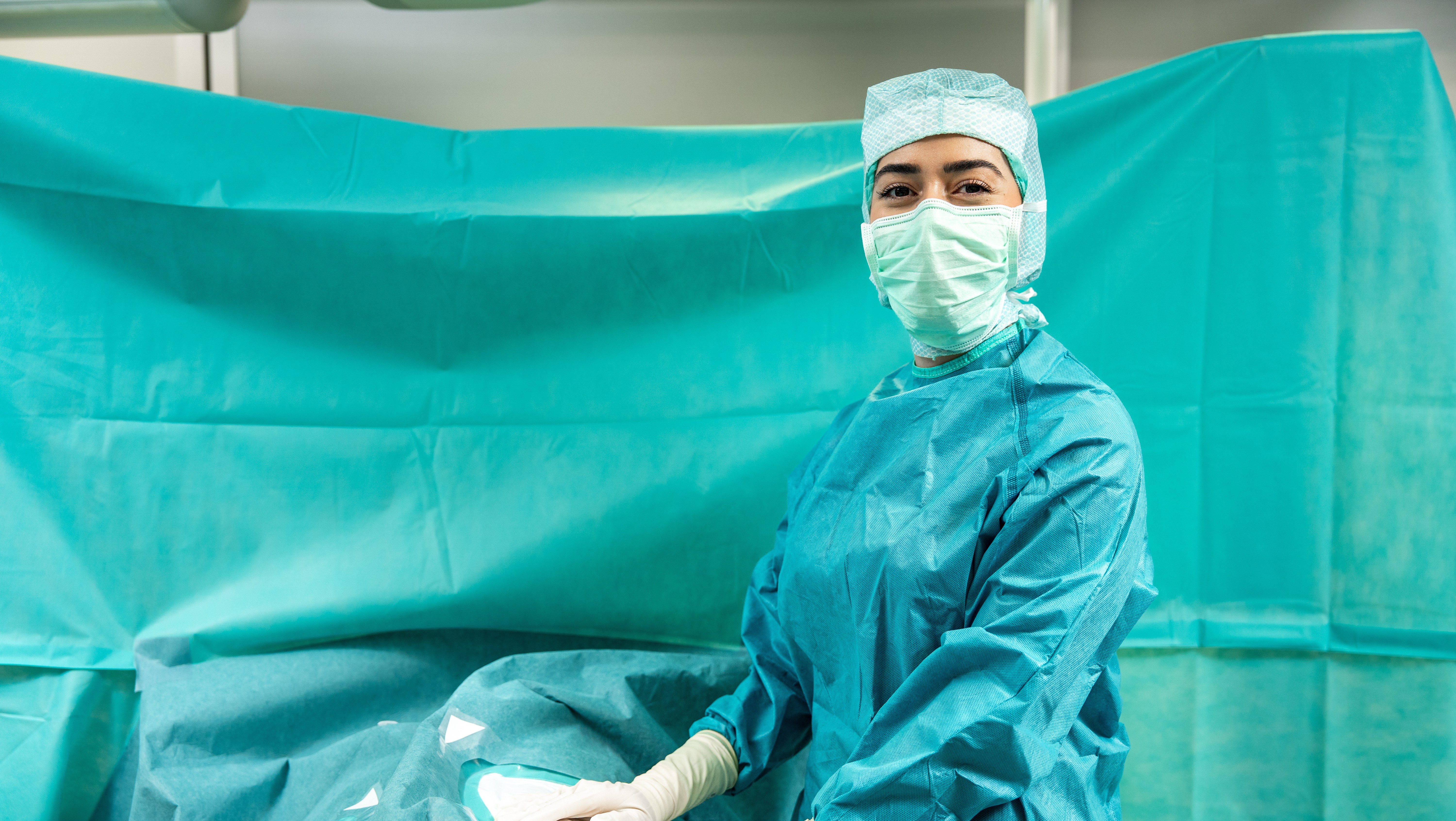 OR professional in surgical clothing arranging a surgical drape