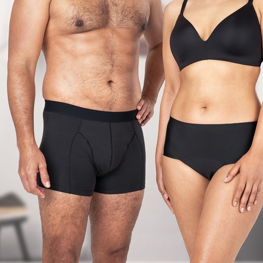 Ein männlicher und ein weiblicher Körper stehen eng nebeneinander. Beide Personen tragen schwarze, saugfähige Unterwäsche von MoliCare®.