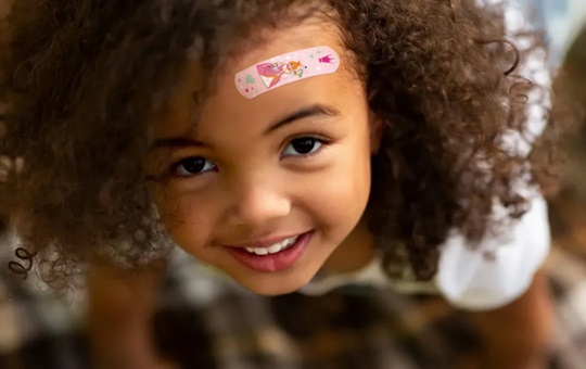 Niña con un strip de Tiritas® playmobil en la frente