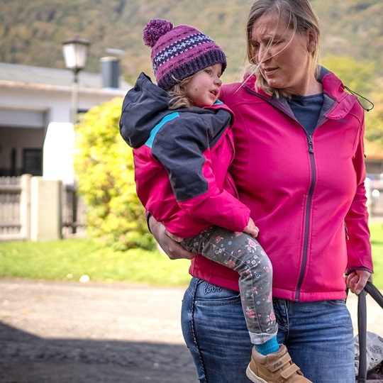 Een moeder draagt haar dochter op haar heup terwijl ze buiten wandelen